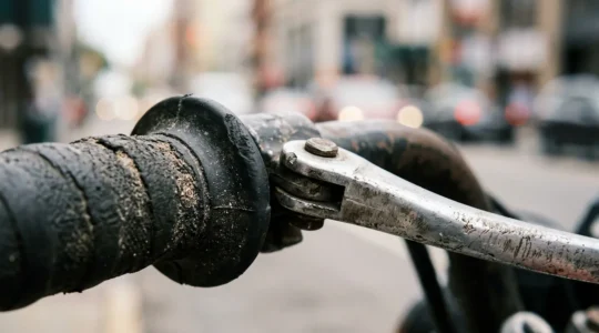 Gros plan sur un guidon de scooter avec poignees et leviers de commande dans un environnement urbain naturel