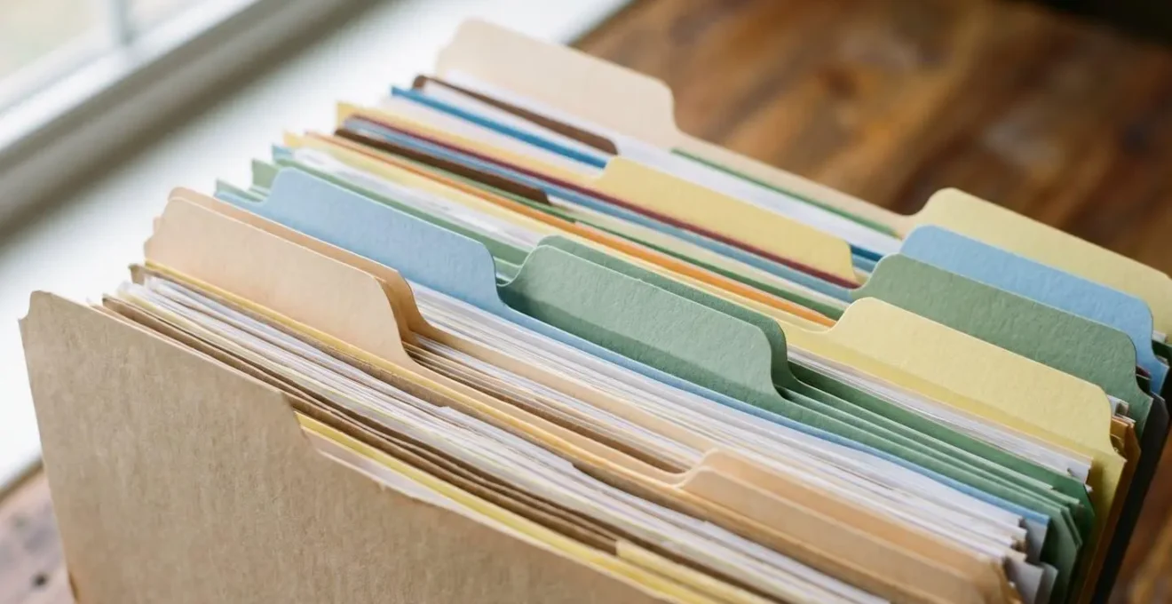 Classeur physique ouvert avec intercalaires colorés organisant documents médicaux et administratifs